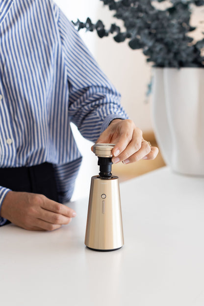 Lifting the cap off the gold Ensō Diffuser to change the fragrance bottle